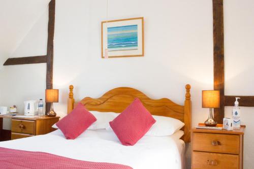 埃文河畔斯特拉特福Moss Cottage的一间卧室配有一张带两个红色枕头的床