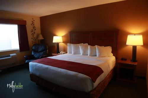 麦卡莱斯特AmericInn by Wyndham McAlester的酒店客房带一张大床和一把椅子