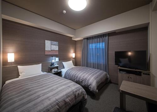 浜田市Hotel Route-Inn Hamada Ekimae的酒店客房设有两张床和一台平面电视。
