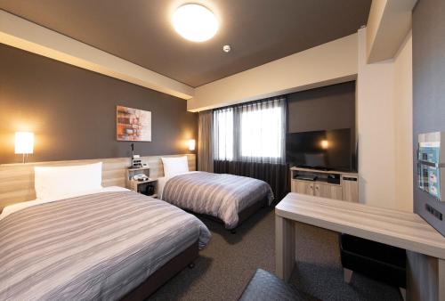 岸和田市Hotel Route-Inn Osaka Kishiwada -Higashikishiwada Ekimae Kansai Airport-的酒店客房设有两张床和一台平面电视。