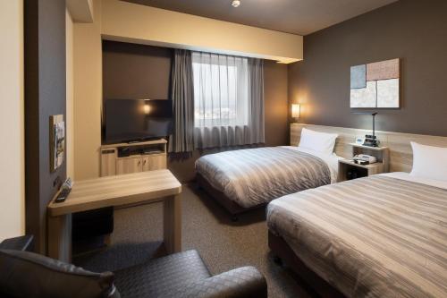YahabaHotel Route-Inn Yahaba的酒店客房设有两张床和电视。