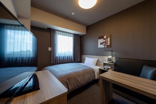 鹿沼Hotel Route-Inn Kanuma Inter的配有一张床和一台平面电视的酒店客房