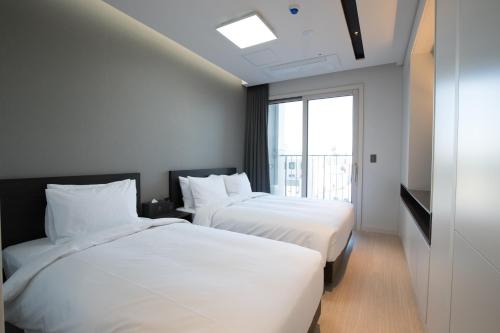 束草市Sunrise Hotel Sokcho的配有窗户的酒店客房内的两张床