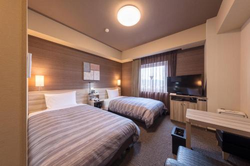仓敷Hotel Route-Inn Kurashiki Mizushima的酒店客房设有两张床和一台平面电视。