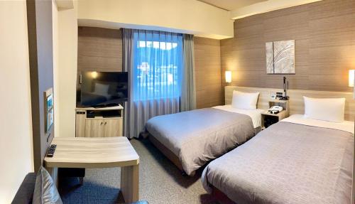 EchizenHotel Route-Inn Takefu Inter的酒店客房设有两张床和一台平面电视。