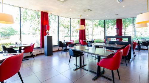 布雷达巴斯通布雷达酒店的餐厅设有红色的椅子和桌子以及窗户。