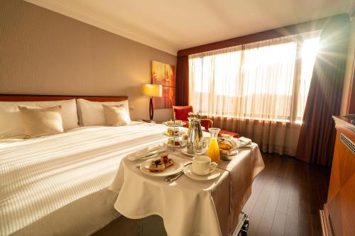 布达佩斯布达佩斯洲际酒店的酒店客房,配有一张带餐桌的床,上面有食物