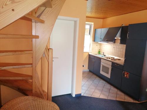 奥特里德维茨Gasthof-Ferienwohnungen-Kliesow´s Reuse的厨房设有楼梯,通往带蓝色橱柜的厨房