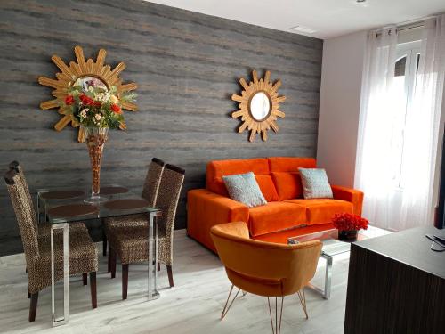 塞维利亚Apartamentos "El Escondite de Triana"的客厅配有橙色沙发和桌子