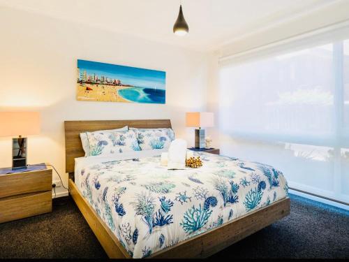 弗兰克斯顿By The Beach Frankston的一间卧室配有一张带蓝色和白色床单的床和窗户。