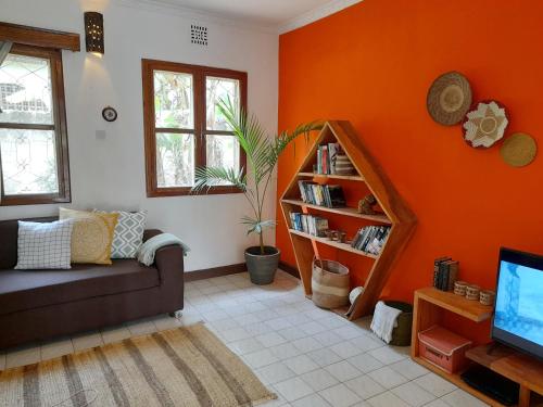 阿鲁沙Utamaduni House B&B的客厅设有橙色的墙壁、沙发和电视
