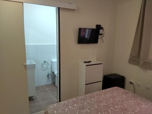 圣伊西德罗Kiki vivienda Bed & breakfast的一间卧室配有一张床,浴室墙上配有电视。