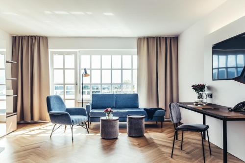 克拉根福Hotel Dermuth Klagenfurt的客厅配有蓝色的沙发和椅子