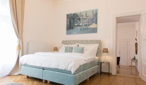 克拉根福Palais Gutenberg la Ville的一间卧室配有一张大床,配有白色的床单和蓝色的点缀。