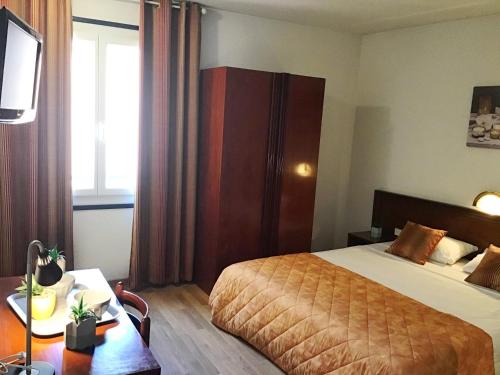 卢尔德Hôtel Angelic的酒店客房配有一张床铺和一张桌子。