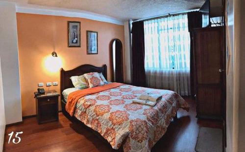 拉塔昆加Hotel Los Ilinizas的一间卧室设有一张大床和一个窗户。