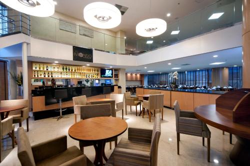 维多利亚Quality Hotel Vitória的一间带桌椅的餐厅和一间酒吧