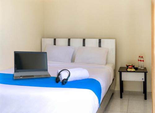 泗水City Residence Kutai 32的一间卧室配有一张带笔记本电脑和耳机的床。