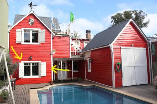 马德普拉塔Habitación en villa neo victoriana con piscina的一座红色的房子,前面有一个游泳池