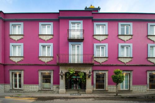 乔卢拉Collection O Las Iglesias, Cholula的粉红色的建筑,设有白色的窗户和阳台