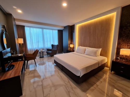 信武里府Chaisaeng Palace Hotel的大型酒店客房,配有一张床和一张书桌
