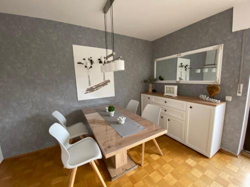 科斯费尔德Ferienwohnung Baumberger-Auszeit的一间带木桌和白色椅子的用餐室