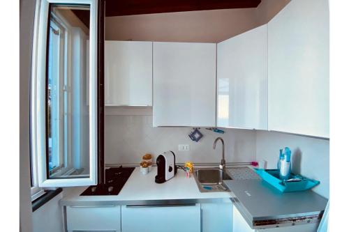 伊斯基亚Dependance Castiglione with pool and view的厨房配有白色橱柜、水槽和窗户。