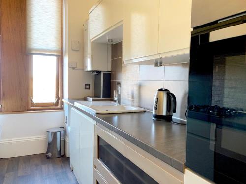 邓迪Tay View Apartment的厨房配有白色橱柜和台面