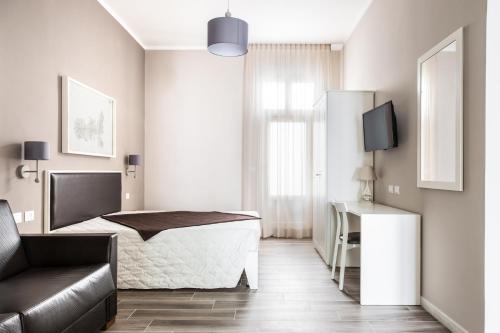 加利波利Faro Bianco Gallipoli Dependance的一间卧室配有一张床、一张沙发和一台电视。