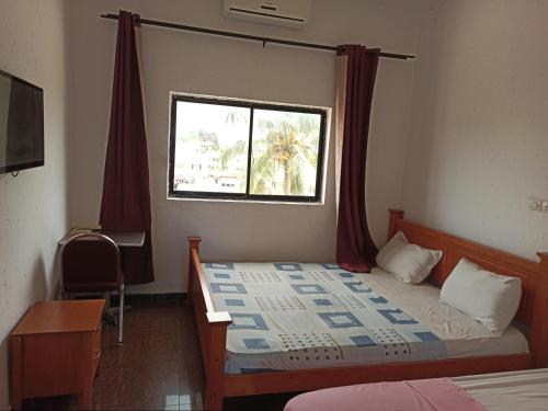 科托努Hotel Saint-Jean的一间卧室配有一张带窗户的床和一张书桌