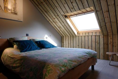 拉罗什-阿登la Nouchettière的一间卧室配有一张带蓝色枕头的床和一扇窗户。