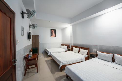 邦美蜀Thanh Ngọc Motel的带三张床、一张桌子和椅子的房间