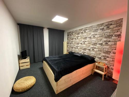 米洛维采WELLNESS APARTMÁN KAROLÍNA的一间卧室设有一张床和砖墙