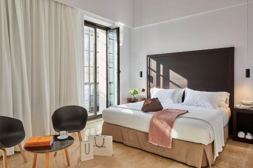 塞维利亚卢赛罗波萨达酒店的一间卧室配有一张大床和两把椅子