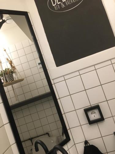 瓦尔韦克B&B de Loeff的浴室设有镜子和白色瓷砖墙