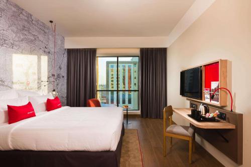 尼兹瓦IntercityHotel Nizwa的酒店客房配有一张床、一张书桌和一台电视。