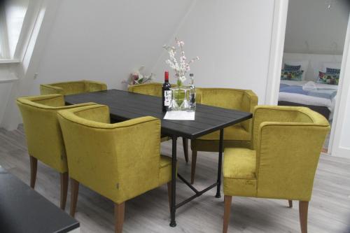 马尔森Bed & Breakfast Geesberge的餐桌、黄色椅子和一瓶葡萄酒