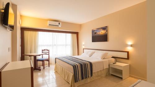 若昂佩索阿Aram Beach & Convention的酒店客房配有一张床铺和一张桌子。