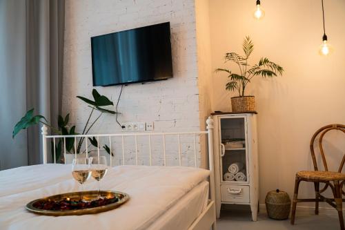 华沙Folk by Anne Apartments & Rooms的一间设有葡萄酒杯和墙上电视的房间