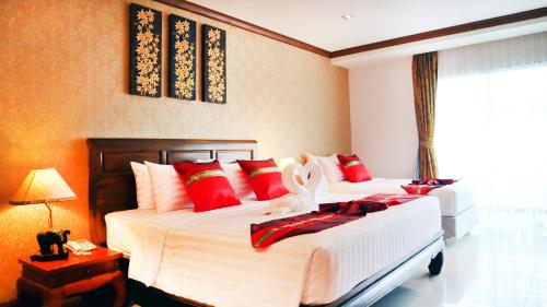 乔木提恩海滩Aiyaree Place Hotel SHA PLUS的一间卧室配有两张带红白色枕头的床