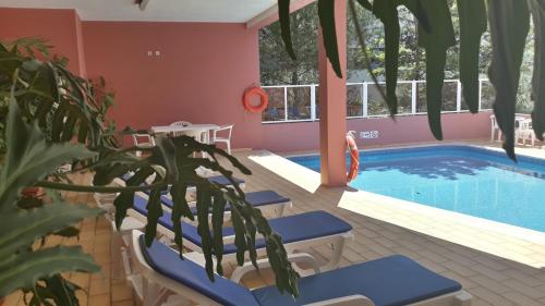 拉戈斯Boutique Hotel Marina S. Roque的一个带蓝色椅子的度假泳池和植物