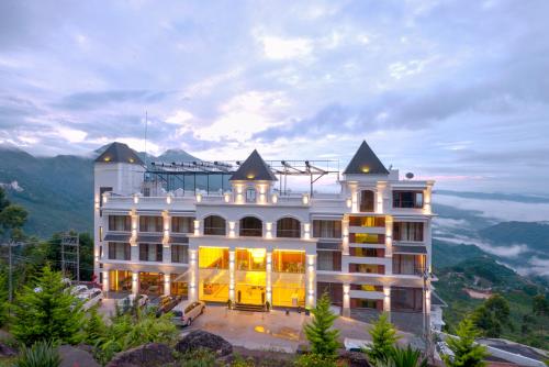 蒙纳Amber Dale Luxury Hotel & Spa, Munnar的山顶上一座白色的大建筑