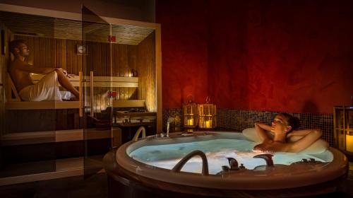奥帕提亚亚得里亚海2号大酒店的男人躺在浴室的浴缸里