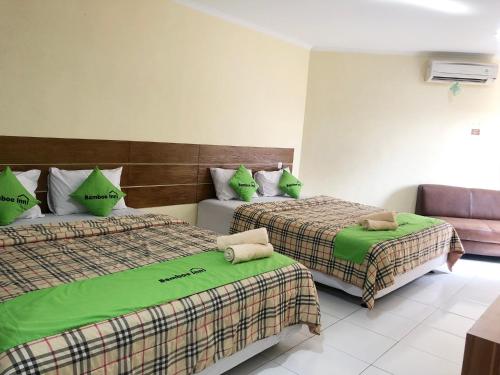 班达楠榜Bamboe Inn Homestay的酒店客房,配有两张带绿床单的床
