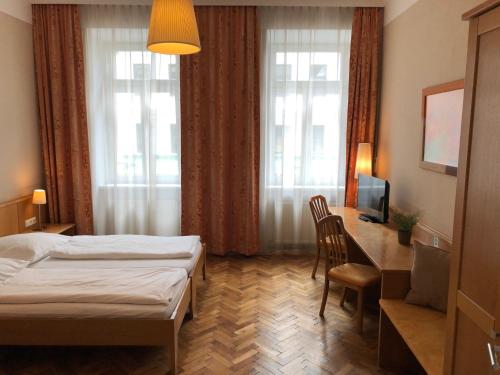 维也纳Gasthof Schwabl Wirt的酒店客房设有一张床、一张书桌和窗户。
