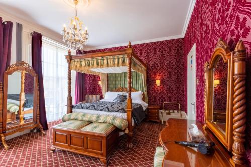 多佛尔休伯特别墅酒店的一间卧室配有天蓬床和红色壁纸