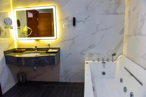 恩德培Admas Grand Hotel的浴室配有盥洗盆、镜子和浴缸