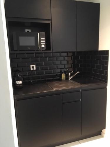 雷恩KastellRen - Maison d'hôtes的黑色厨房配有水槽和微波炉