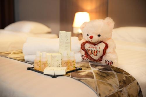 莎阿南Cosy private suite 2BR 591 Nexus USJ Shah Alam的泰迪熊坐在床上,带蜡烛的托盘
