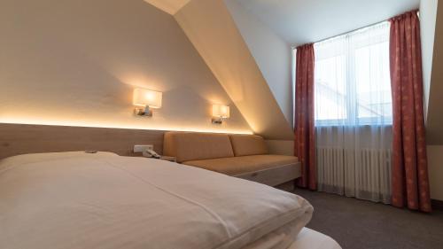 慕尼黑卢特尔酒店的一间卧室配有一张床、一张沙发和一个窗口